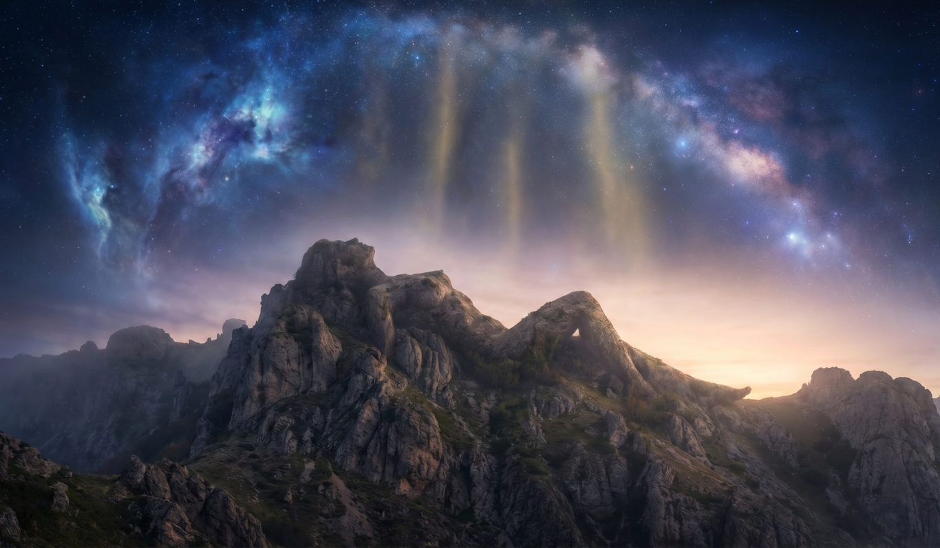 Sternenhimmel über majestätischen Bergen im Dämmerlicht.